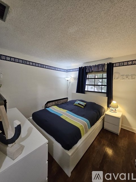 A bedroom with a bed, nightstand, and lamp.