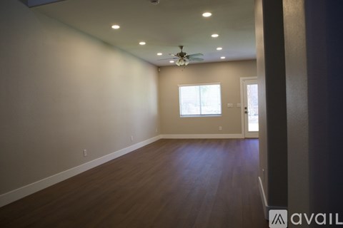 A spacious room with wooden flooring and a ceiling fan.