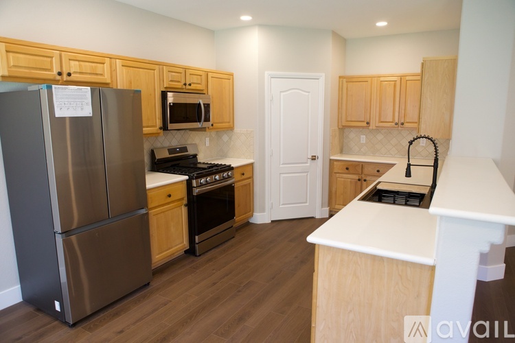 A kitchen with wooden cabinets and a stainless steel refrigerator.