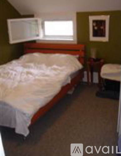 A bedroom with a bed, chair, and window.