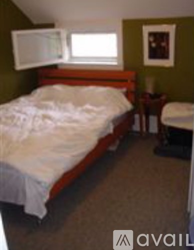 A bedroom with a bed, chair, and window.