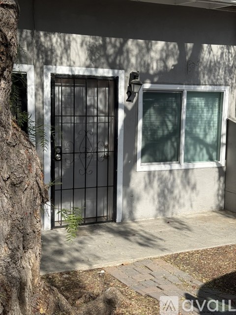 A tree trunk is on the left side of a gate.