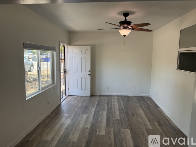 A room with a ceiling fan and wooden flooring.