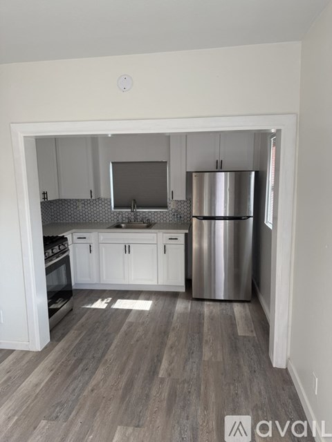 A kitchen with white cabinets and a wooden floor.