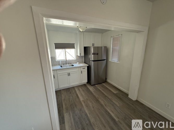 A kitchen with a refrigerator, cabinets, and a window.