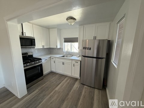 A kitchen with white cabinets and a stainless steel refrigerator.