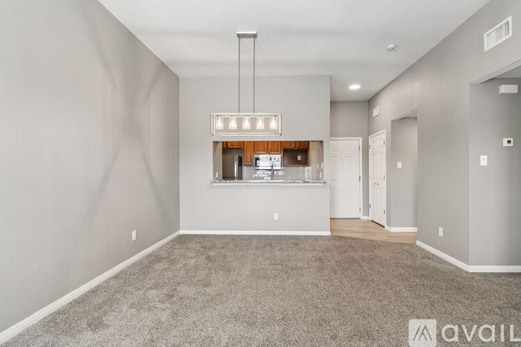 A spacious living room with a grey carpet and a large window.
