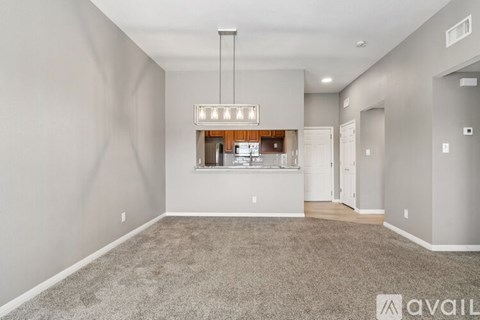 A spacious living room with a grey carpet and a large window.