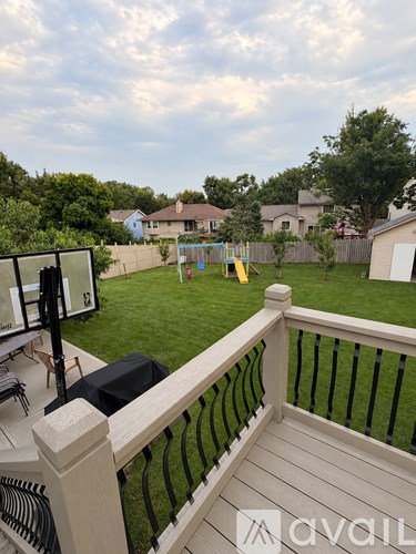 A patio with a black umbrella and a playground in the backyard.