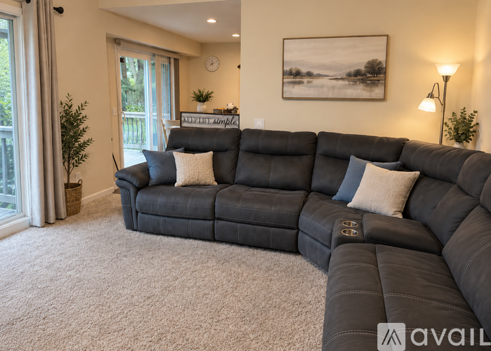 A living room with a large black sofa and a painting on the wall.