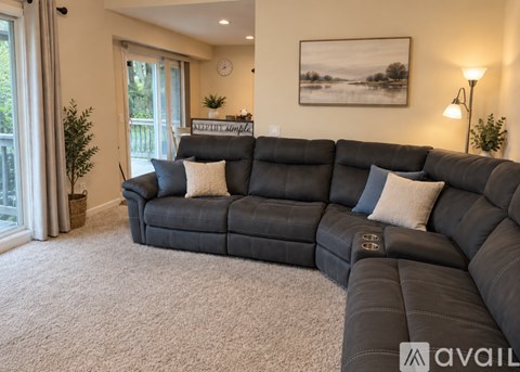 A living room with a large black sofa and a painting on the wall.