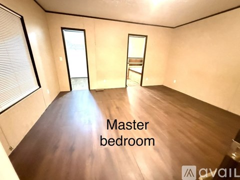 A master bedroom with wooden floors and a window.