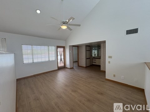 A spacious room with a ceiling fan and wooden flooring.