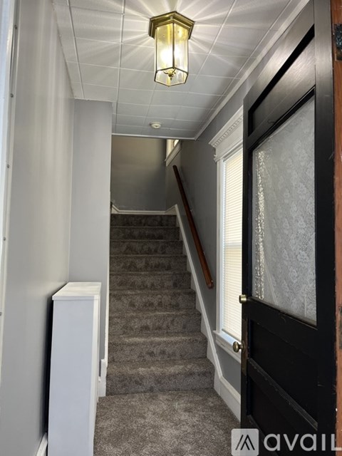 A hallway with a staircase and a light on the ceiling.