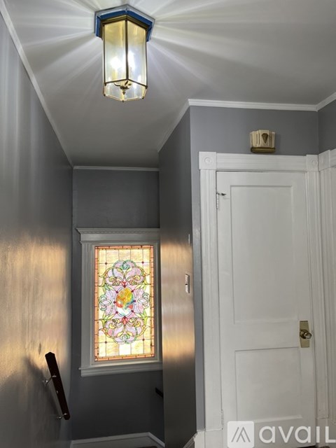 A stained glass window in a hallway with a white door.
