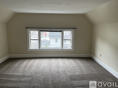 A room with a carpeted floor and a window with blinds.