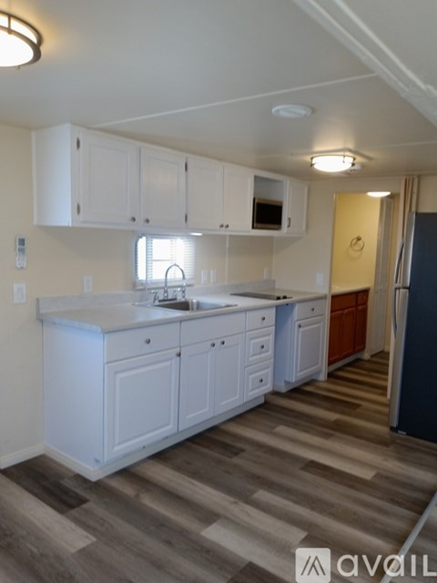 A kitchen with white cabinets and a wooden floor.