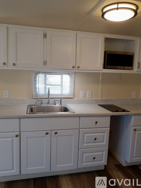 A kitchen with white cabinets and a sink under a window.