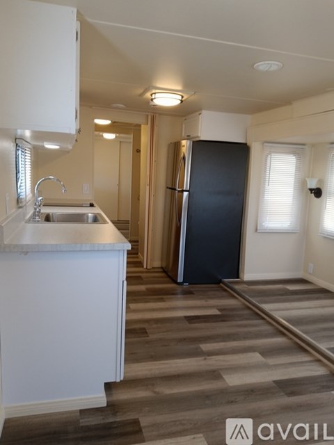 A kitchen with a black refrigerator and white countertops.