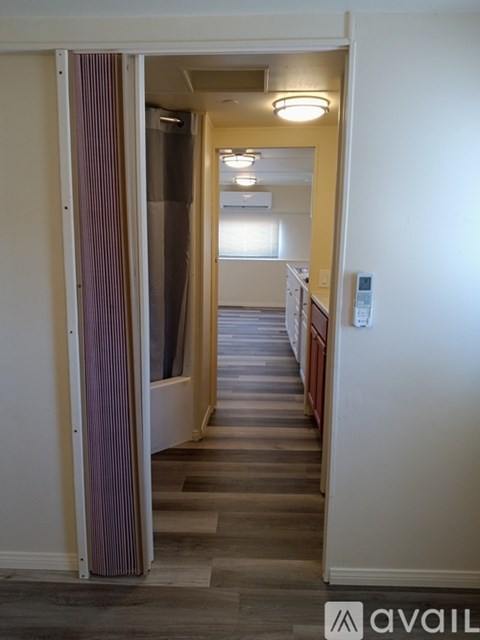 A hallway with a light on the wall and a door open to another room.