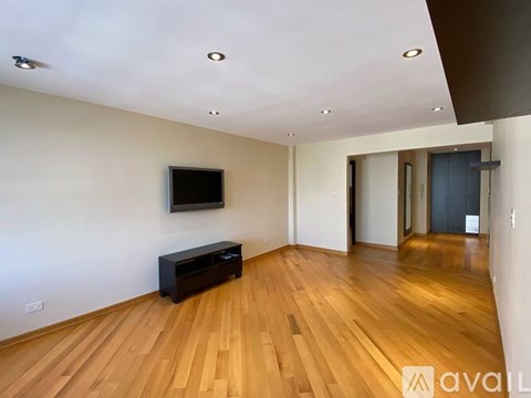 A spacious room with wooden floors and a television mounted on the wall.