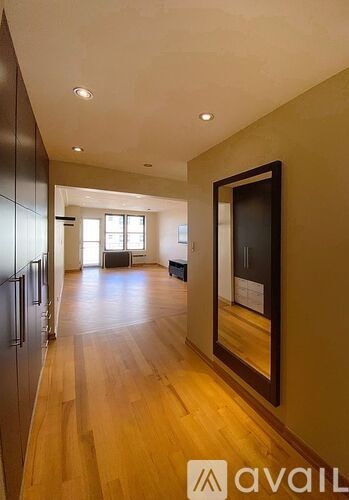 A hallway with wooden floors and a mirror on the wall.