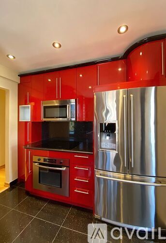 A kitchen with red cabinets and stainless steel appliances.
