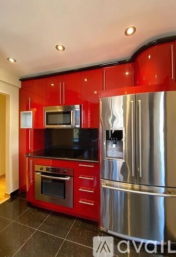 A kitchen with red cabinets and stainless steel appliances.