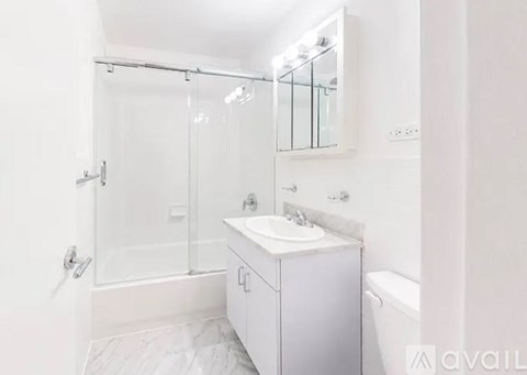 A white bathroom with a sink, mirror, and shower.