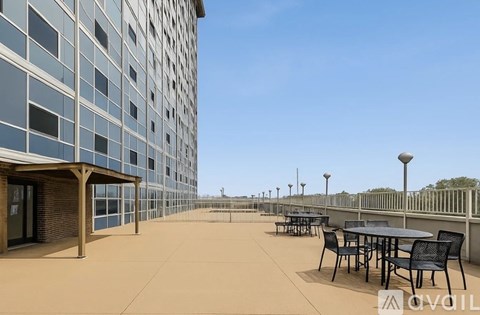 A patio area with tables and chairs is in front of a tall building.