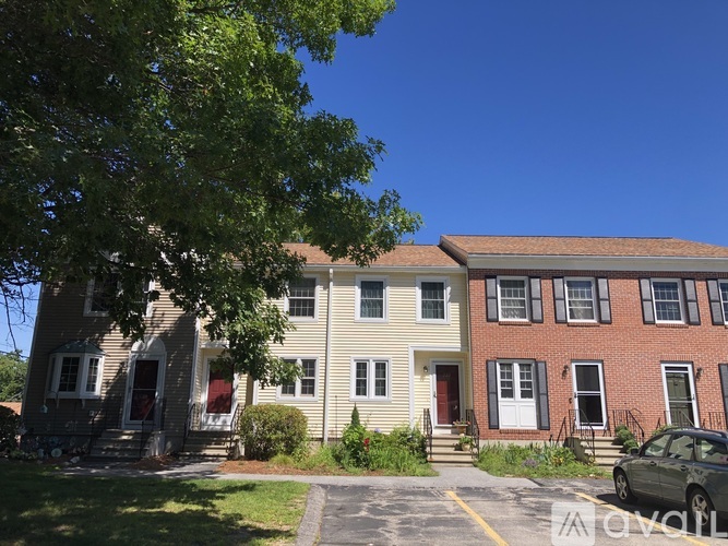 A row of houses with a car parked in front of the red brick house.