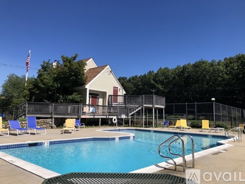 A pool with a house in the background and chairs around the pool.