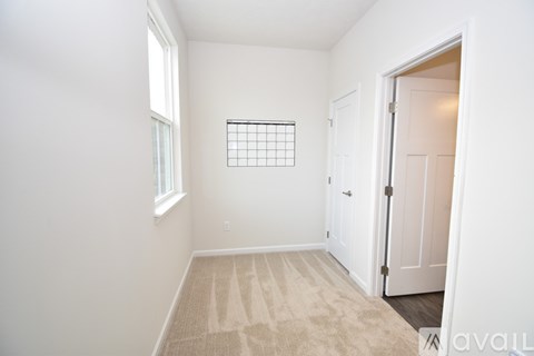A room with a carpet, a window, and a door.