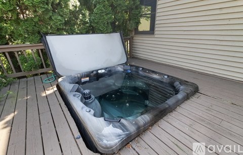 A hot tub on a wooden deck with the lid open.