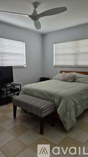A bedroom with a bed, a ceiling fan, and a television.