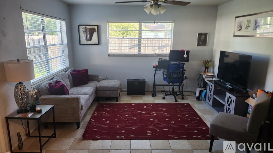 A living room with a couch, a television, and a ceiling fan.
