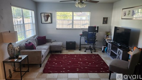 A living room with a couch, a television, and a ceiling fan.