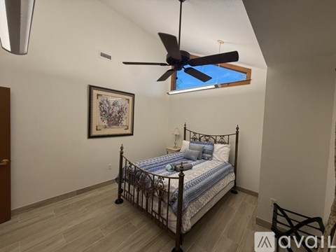 A bedroom with a bed, a ceiling fan, and a picture on the wall.