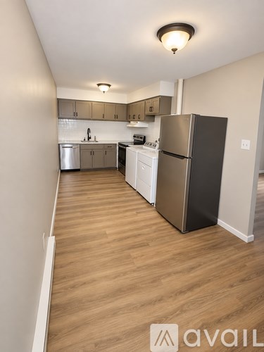 A kitchen with a black refrigerator and wooden floors.