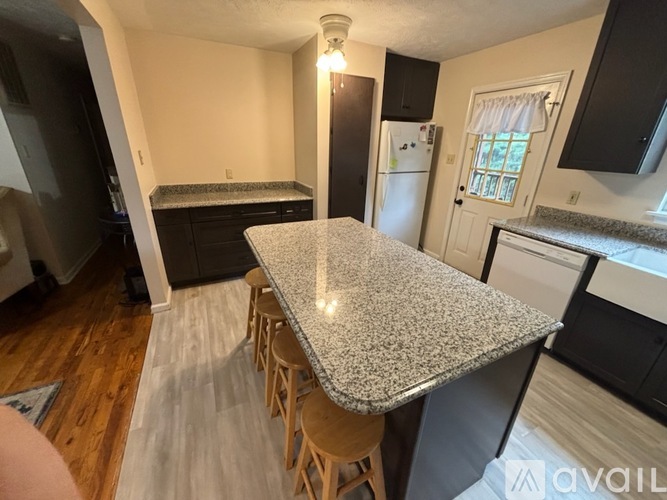A kitchen with a granite countertop and wooden floors.