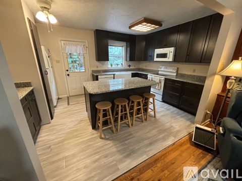 A kitchen with a white island and wooden stools.