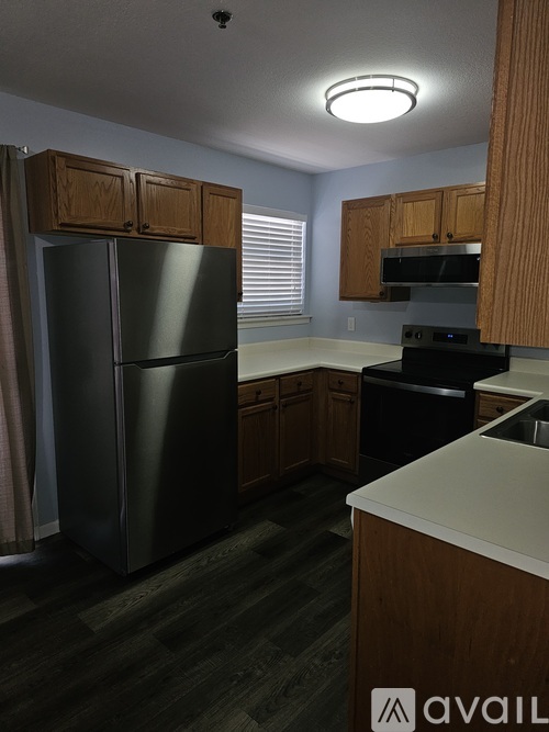 A kitchen with a black refrigerator and wooden cabinets.