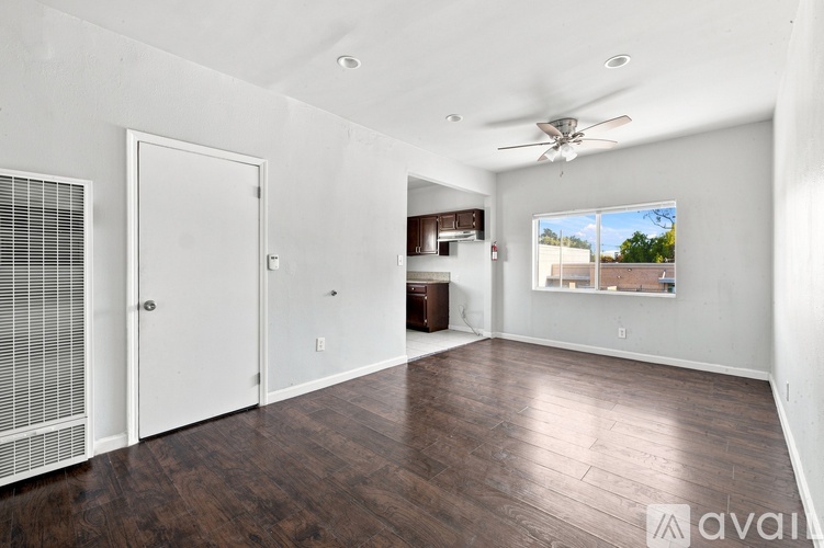 A spacious room with a ceiling fan and a window overlooking a building.