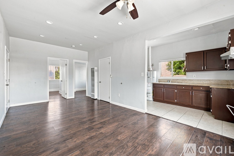 A spacious, empty room with wood flooring and a ceiling fan.