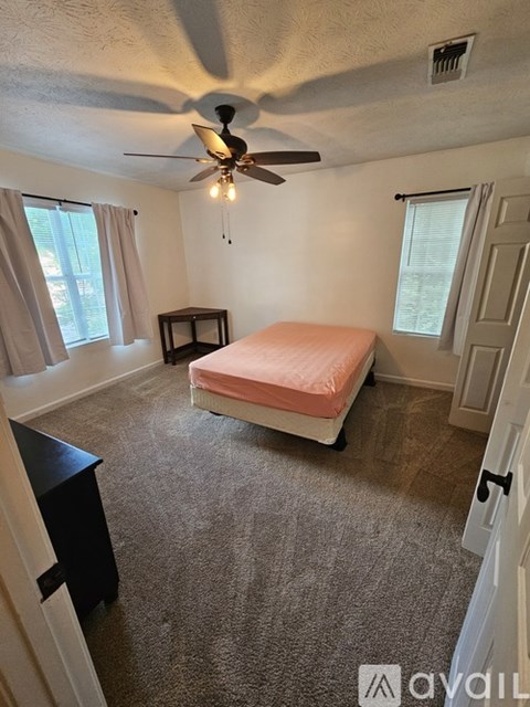 A bedroom with a bed, a ceiling fan, and a small table.