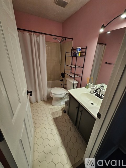 A bathroom with pink walls and a white door.