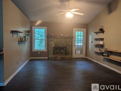 A spacious room with a fireplace and a ceiling fan.