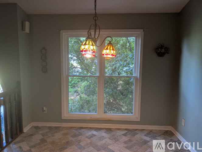 A room with a window and a hanging light fixture.