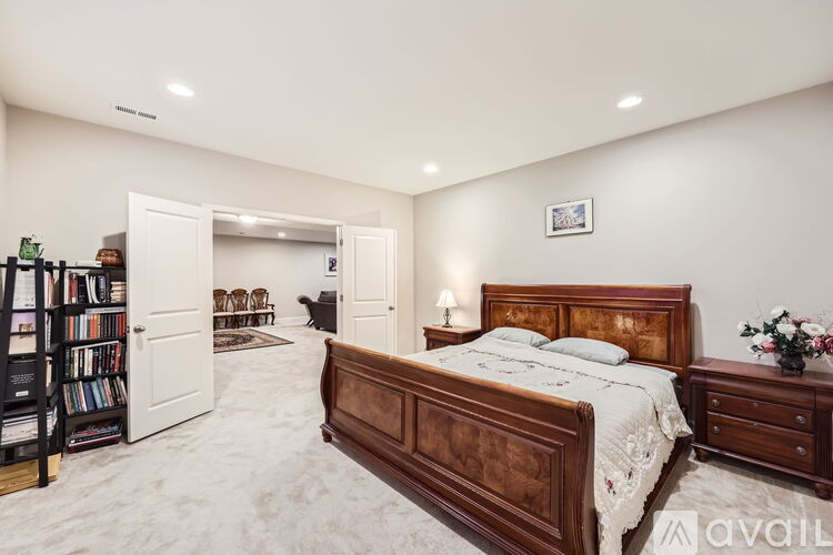 A bedroom with a large bed, a bookshelf, and a nightstand.