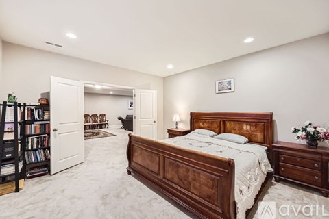 A bedroom with a large bed, a bookshelf, and a nightstand.